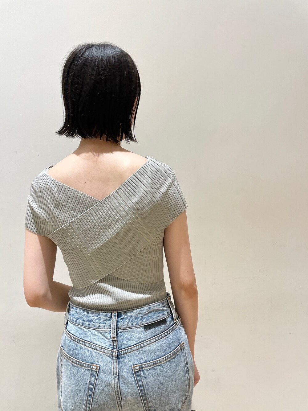 グリーン系のニット/セーター、ブルー系のデニムパンツ、ブラック系のハンドバッグを着用したレディースの夏コーディネートの7枚目の写真