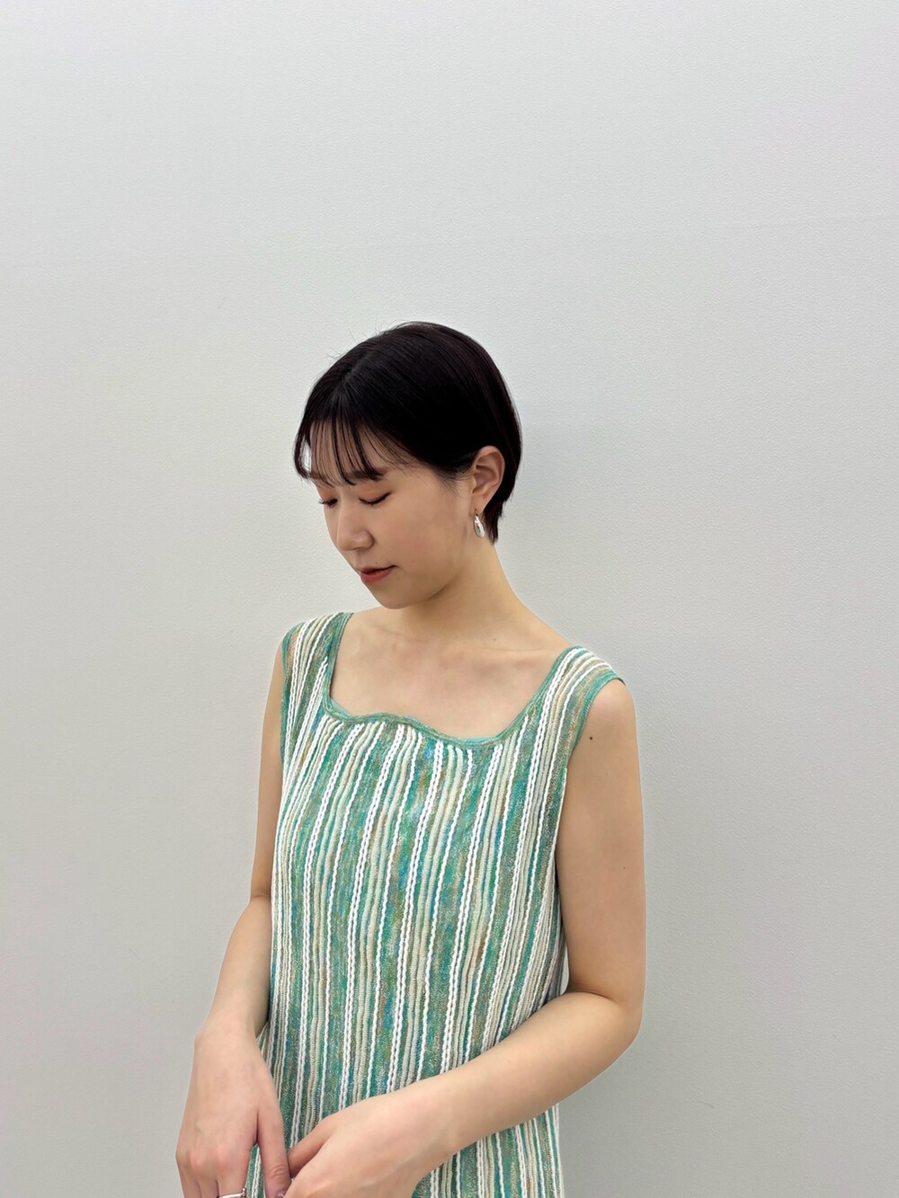 グリーン系のワンピース、ホワイト系のサンダル、シルバー系のピアス（両耳用）を着用したレディースの春コーディネートの4枚目の写真