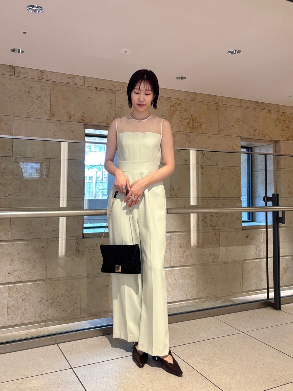 ブラック系のクラッチバッグ、ブラウン系のパンプス、グリーン系のパンツドレスを着用したレディースの秋コーディネートの7枚目の写真