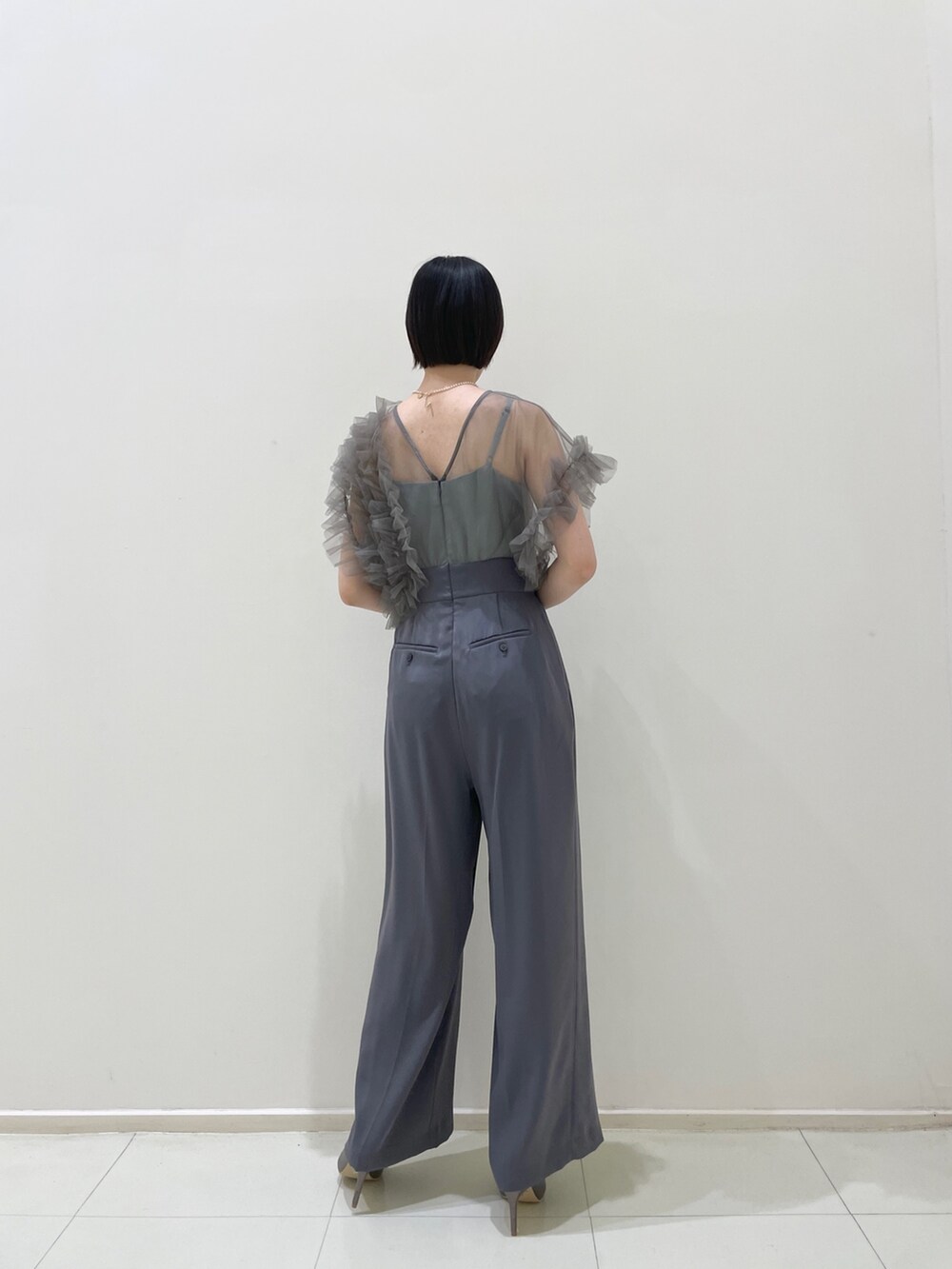 グレー系のパンツドレス、シルバー系のハンドバッグ、シルバー系のパンプスを着用したレディースの春コーディネートの4枚目の写真