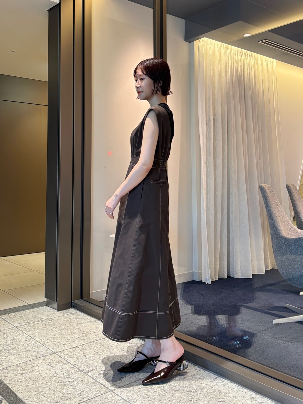 ブラウン系のジャンパースカート、ブラウン系のパンプス、ブラウン系のボストンバッグを着用したレディースの夏コーディネートの3枚目の写真