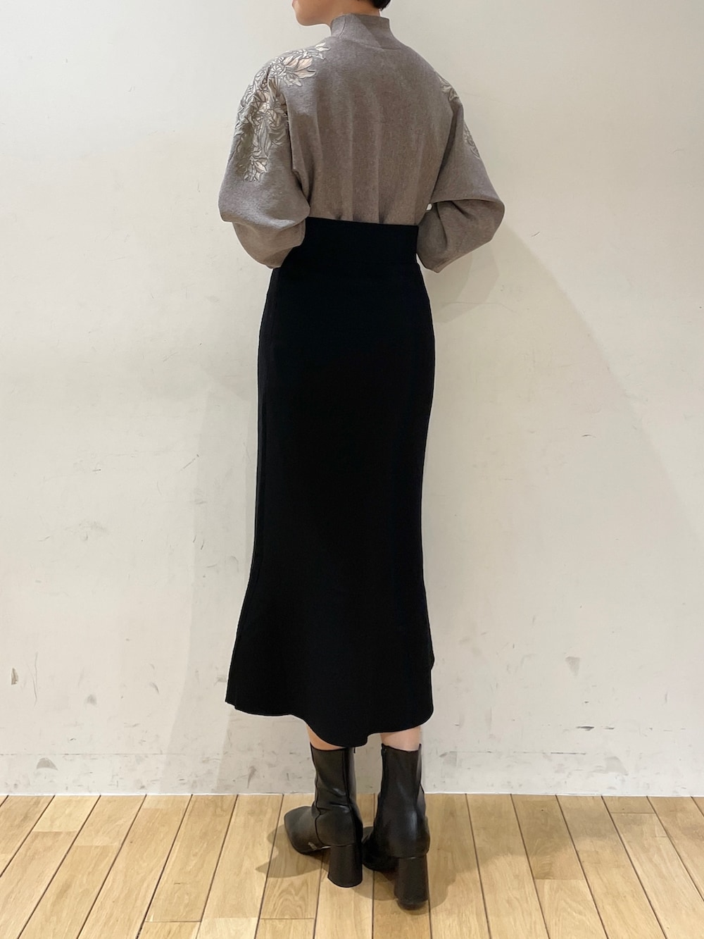 ブラック系のスカート、グレー系のニット/セーター、ブラック系のブーツを着用したレディースの冬コーディネートの5枚目の写真