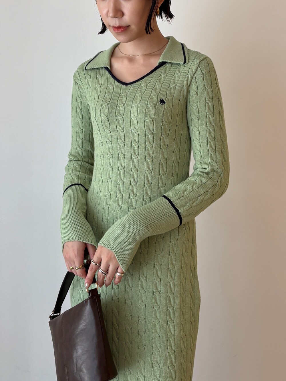 グリーン系のワンピース、ブラック系のステンカラーコート、ブラウン系のブーツを着用したレディースの秋コーディネートの9枚目の写真