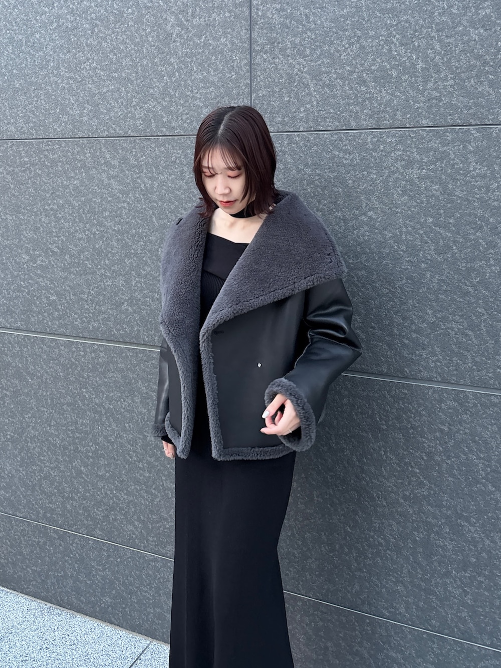 ブラック系のワンピース、グレー系のムートンコートを着用したレディースの冬コーディネートの7枚目の写真