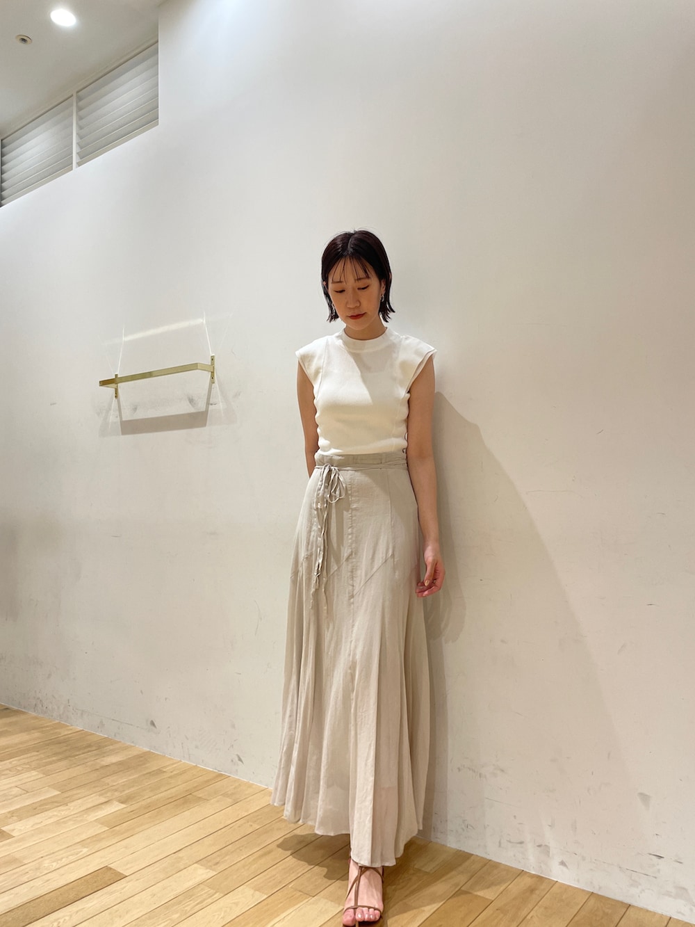 イエロー系のサンダル、グレー系のスカート、ホワイト系のニット/セーターを着用したレディースの夏コーディネートの4枚目の写真