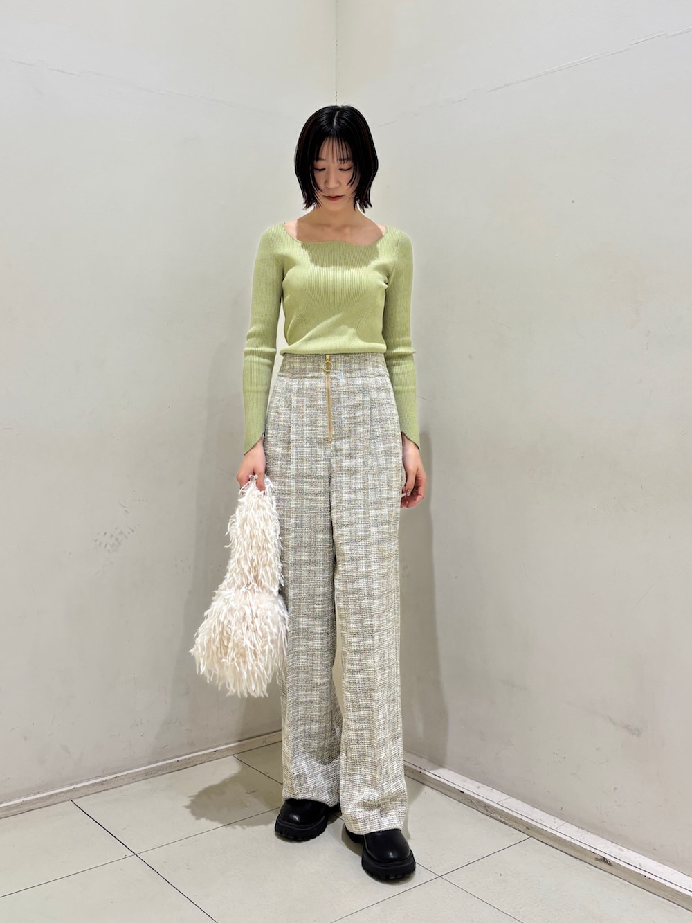 ホワイト系のその他パンツ、グリーン系のニット/セーター、ホワイト系のハンドバッグを着用したレディースの冬コーディネートの2枚目の写真