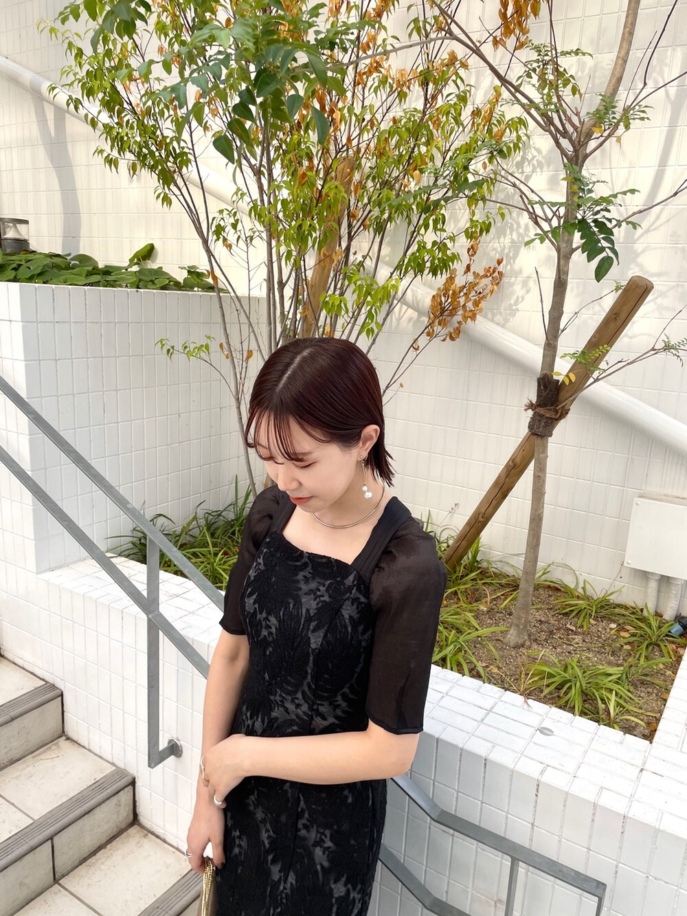ゴールド系のハンドバッグ、その他のパンプス、ブラック系のドレスを着用したレディースの秋コーディネートの6枚目の写真
