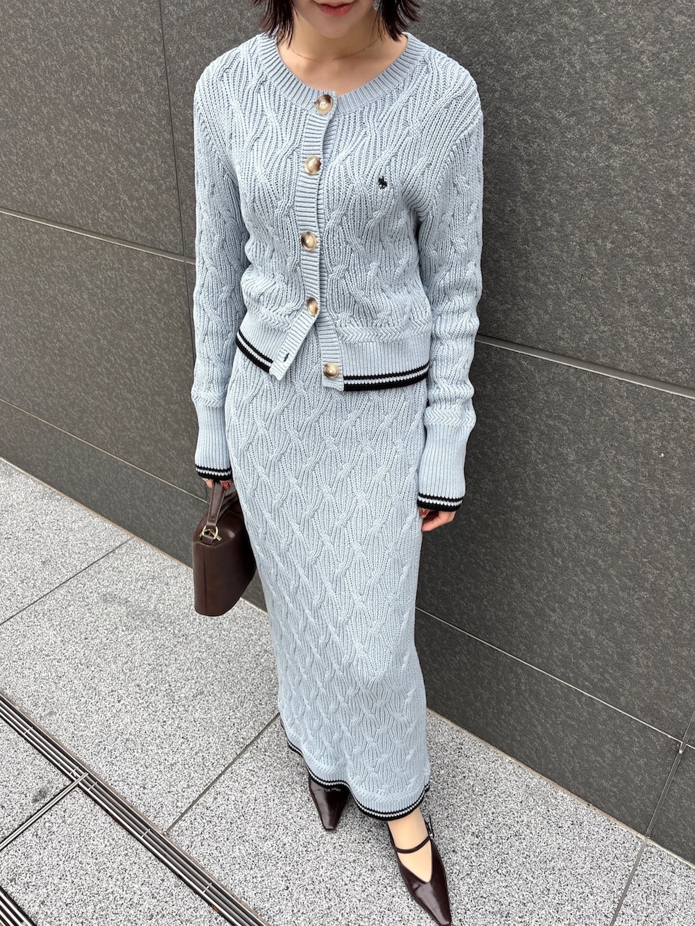 ブルー系のワンピース、ブラウン系のハンドバッグ、ブラウン系のパンプスを着用したレディースの冬コーディネートの5枚目の写真