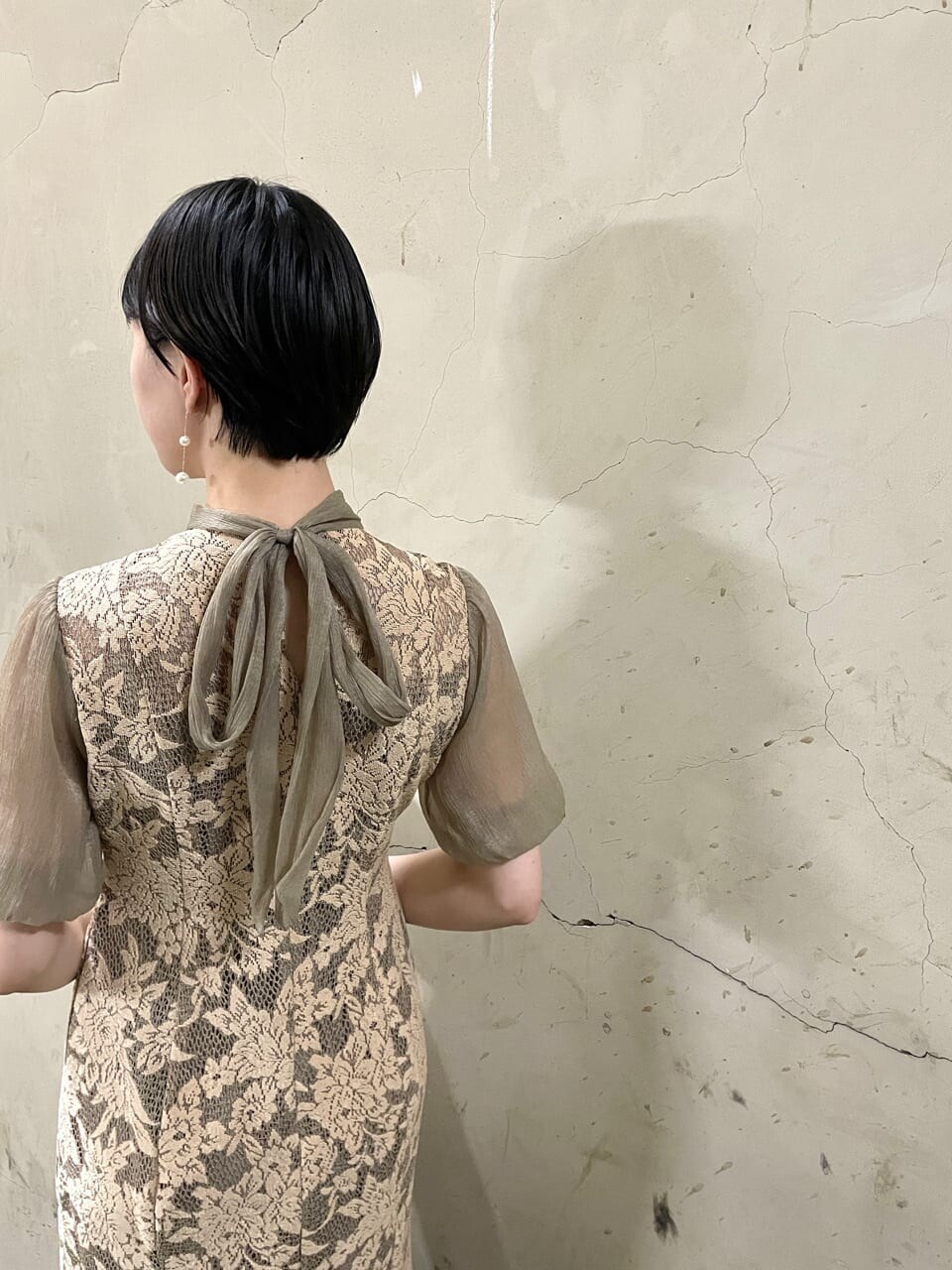 ベージュ系のドレス、ゴールド系のパンプス、ベージュ系のクラッチバッグを着用したレディースの秋コーディネートの8枚目の写真