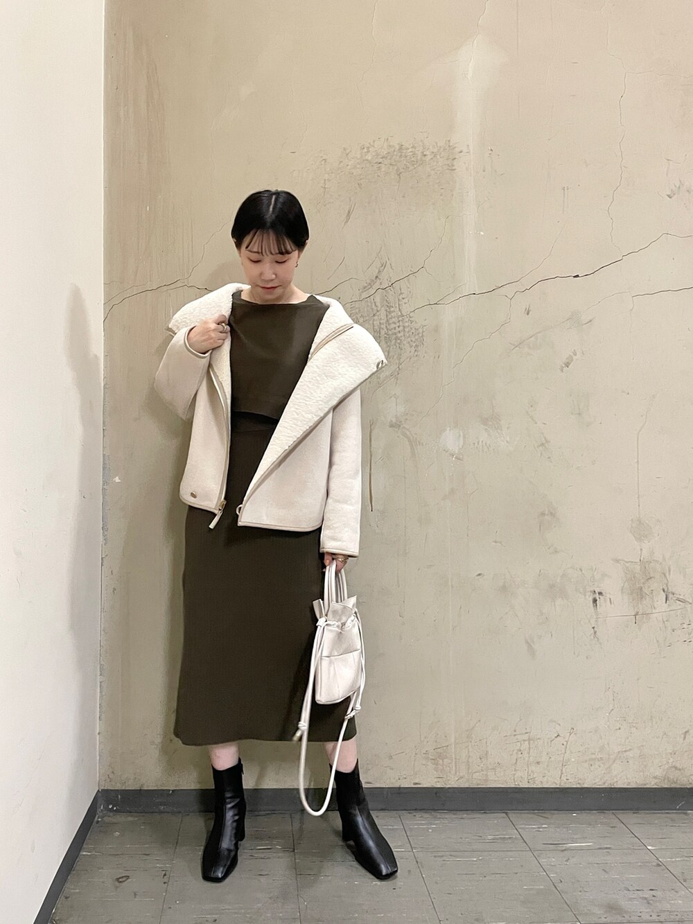 ブラウン系のワンピース、ブラック系のブーツ、ホワイト系のハンドバッグを着用したレディースの秋コーディネートの9枚目の写真