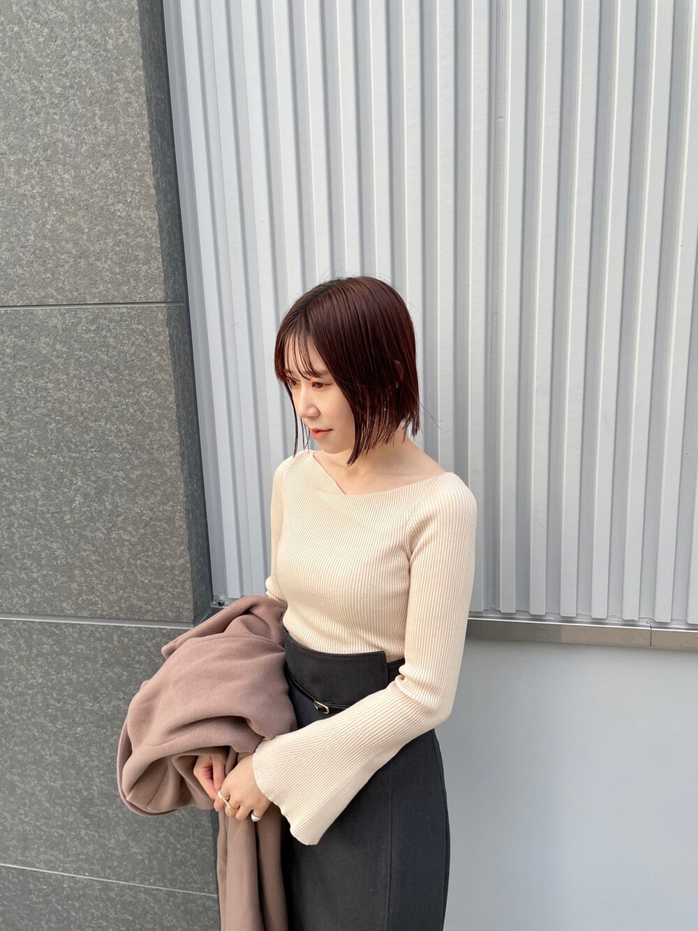 ホワイト系のニット/セーター、ブラウン系のチェスターコート、グレー系のスカートを着用したレディースの冬コーディネートの6枚目の写真