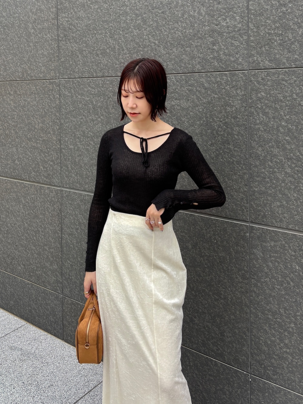 ホワイト系のスカート、ブラック系のニット/セーター、イエロー系のハンドバッグを着用したレディースの秋コーディネートの5枚目の写真