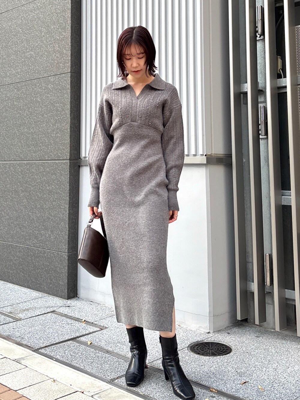 グレー系のワンピース、ブラウン系のハンドバッグ、ブラック系のブーツを着用したレディースの冬コーディネートの6枚目の写真