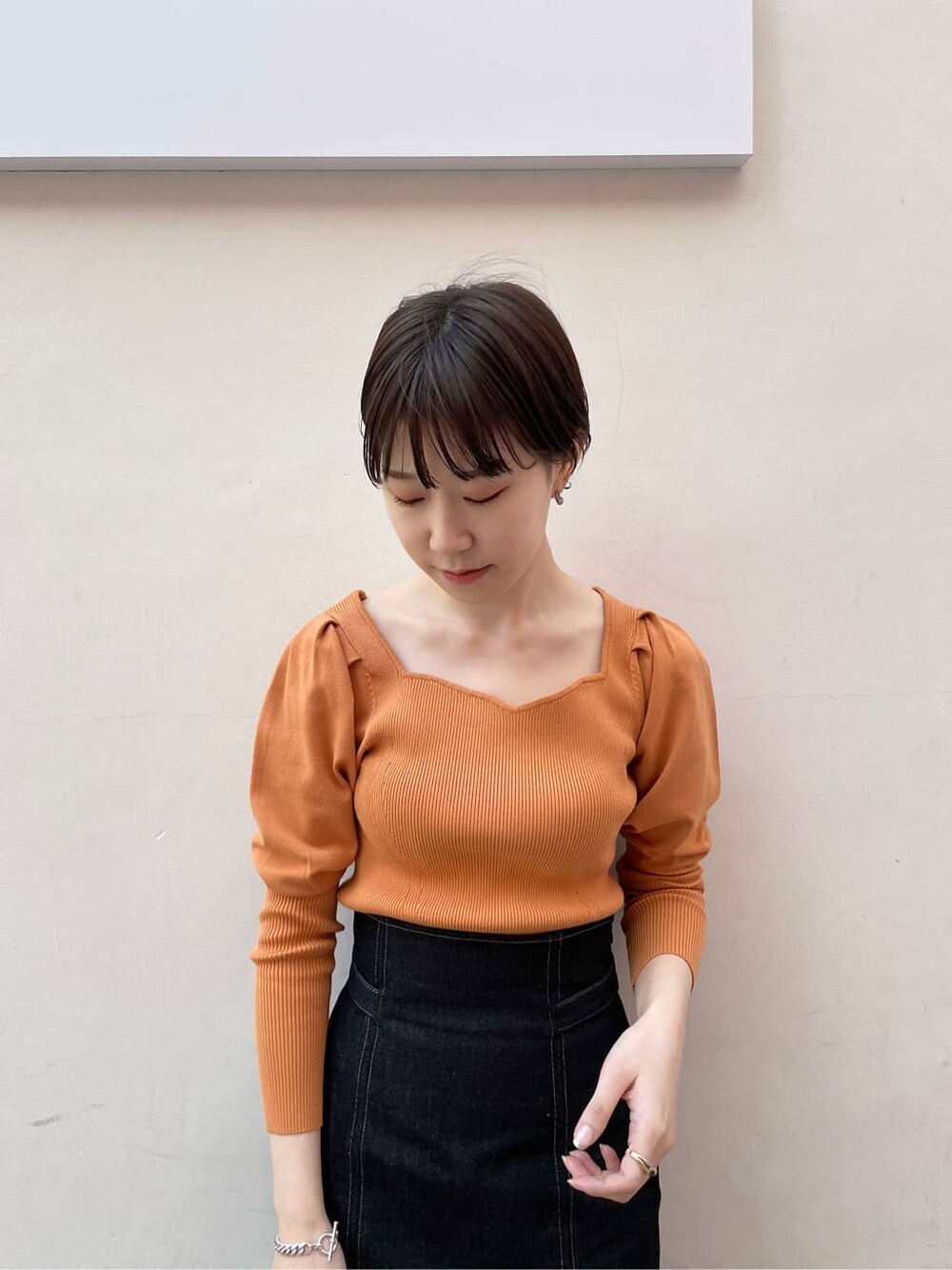 ブラック系のその他シューズ、オレンジ系のニット/セーター、ブラック系のスカートを着用したレディースの冬コーディネートの6枚目の写真