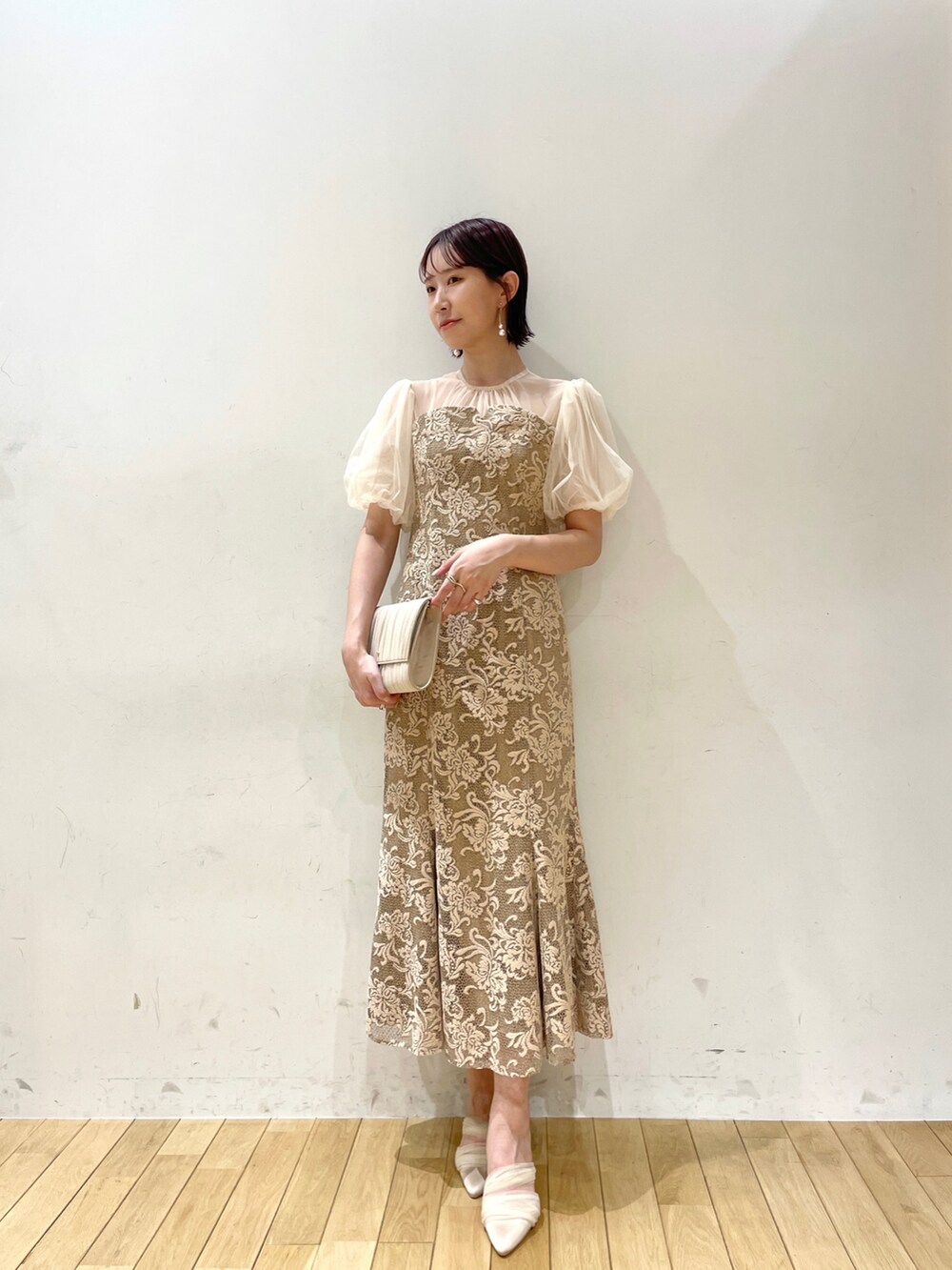 ベージュ系のハンドバッグ、ベージュ系のパンプス、ベージュ系のドレスを着用したレディースの秋コーディネートの2枚目の写真