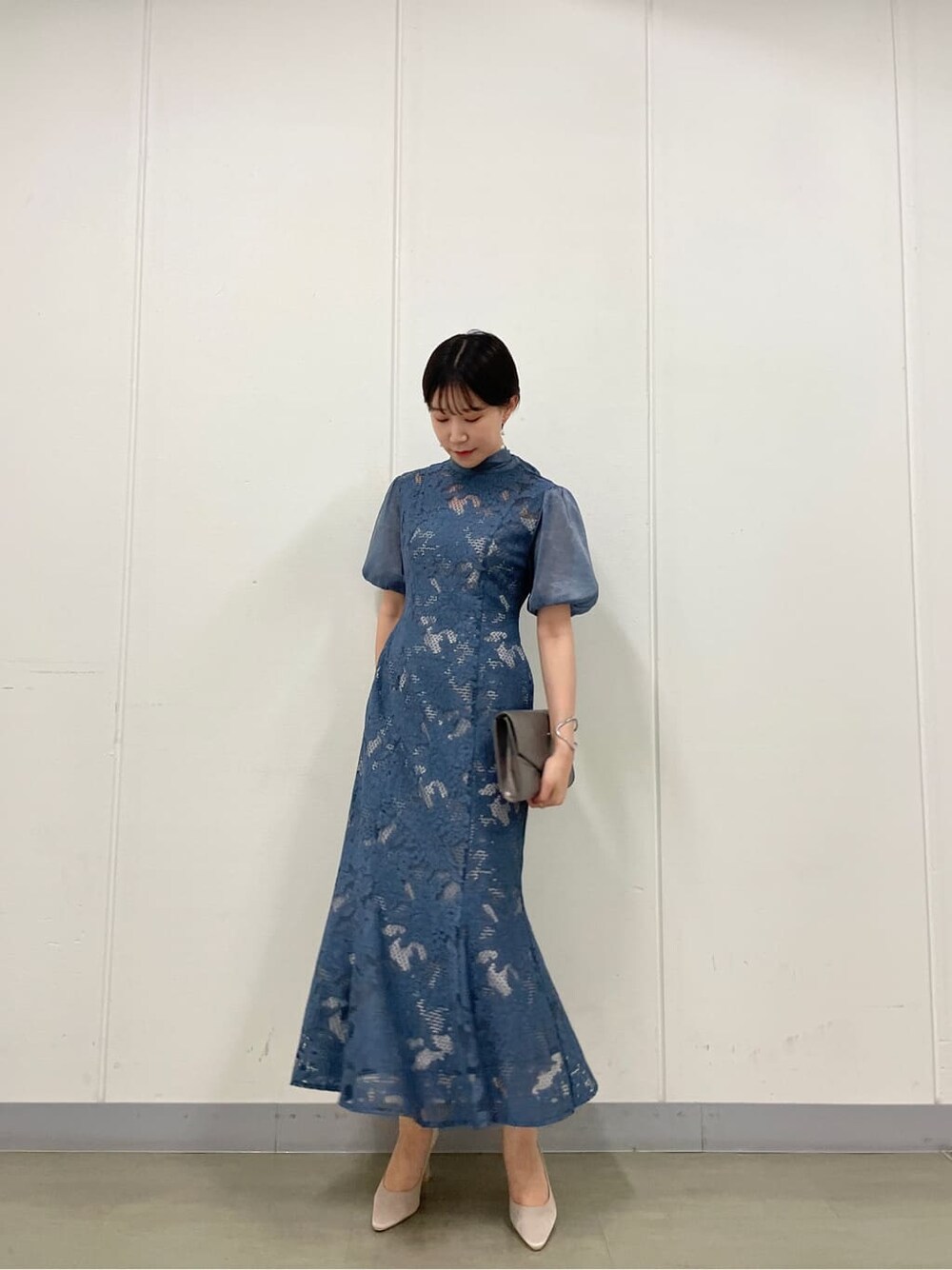 シルバー系のクラッチバッグ、ベージュ系のパンプス、ブルー系のドレスを着用したレディースの夏コーディネートの2枚目の写真