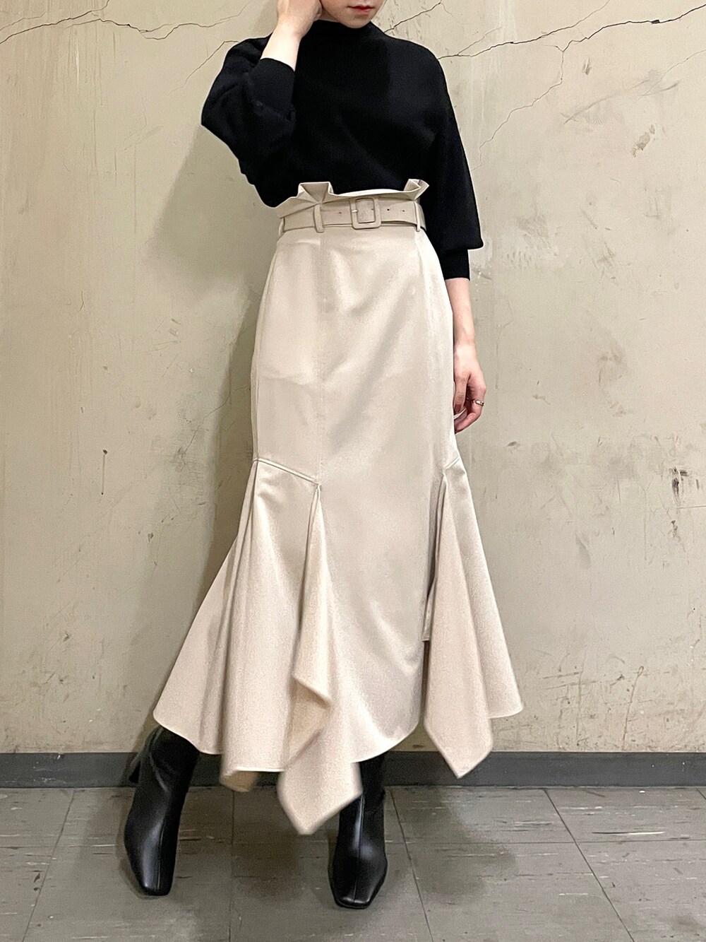 ベージュ系のスカート、ブラック系のニット/セーター、ブラック系のブーツを着用したレディースの秋コーディネートの3枚目の写真