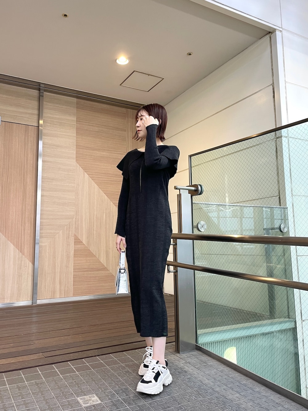 ブラック系のワンピース、ブラック系のスニーカー、シルバー系のショルダーバッグを着用したレディースの春コーディネートの2枚目の写真