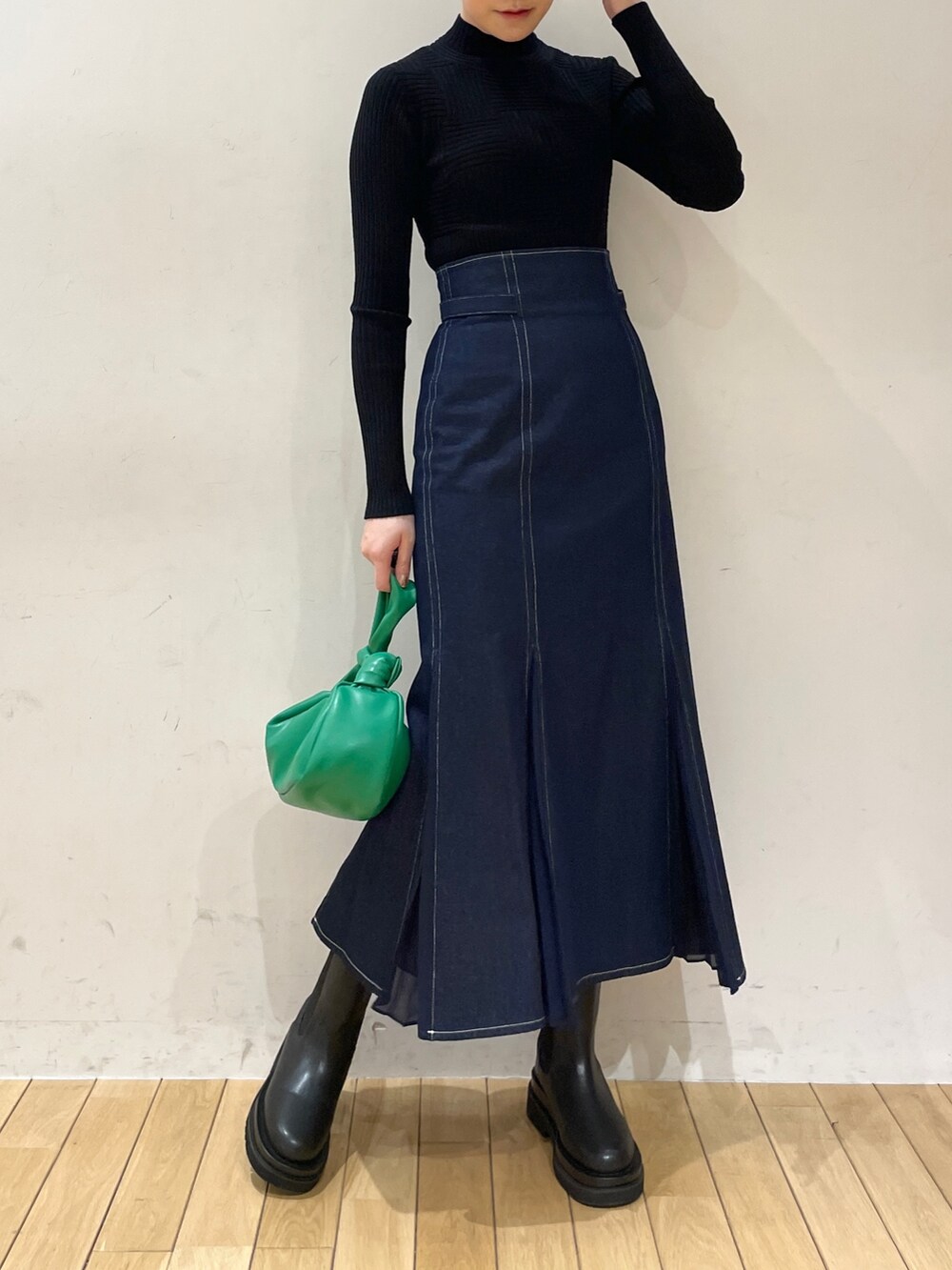 ブルー系のスカート、ブラック系のニット/セーター、グリーン系のハンドバッグを着用したレディースの冬コーディネートの5枚目の写真