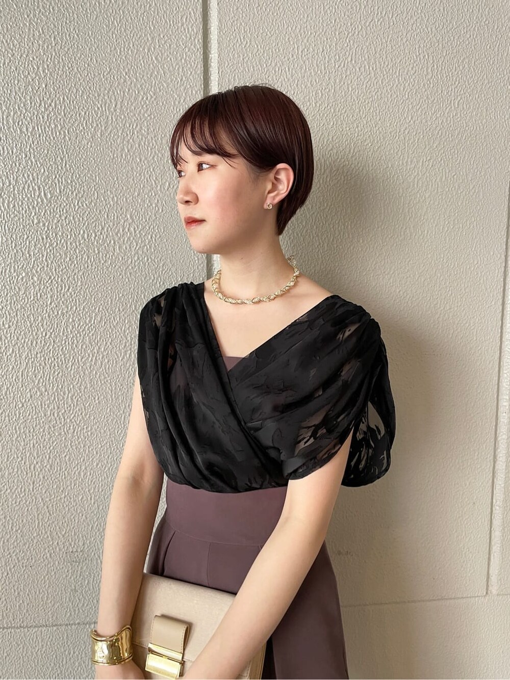 パープル系のパンツドレス、シルバー系のパンプス、ベージュ系のクラッチバッグを着用したレディースの春コーディネートの7枚目の写真
