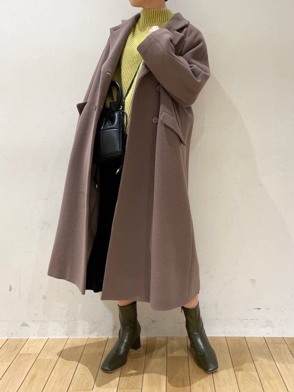 イエロー系のニット/セーター、ブラック系のスカート、ブラック系のハンドバッグを着用したレディースの冬コーディネートの7枚目の写真