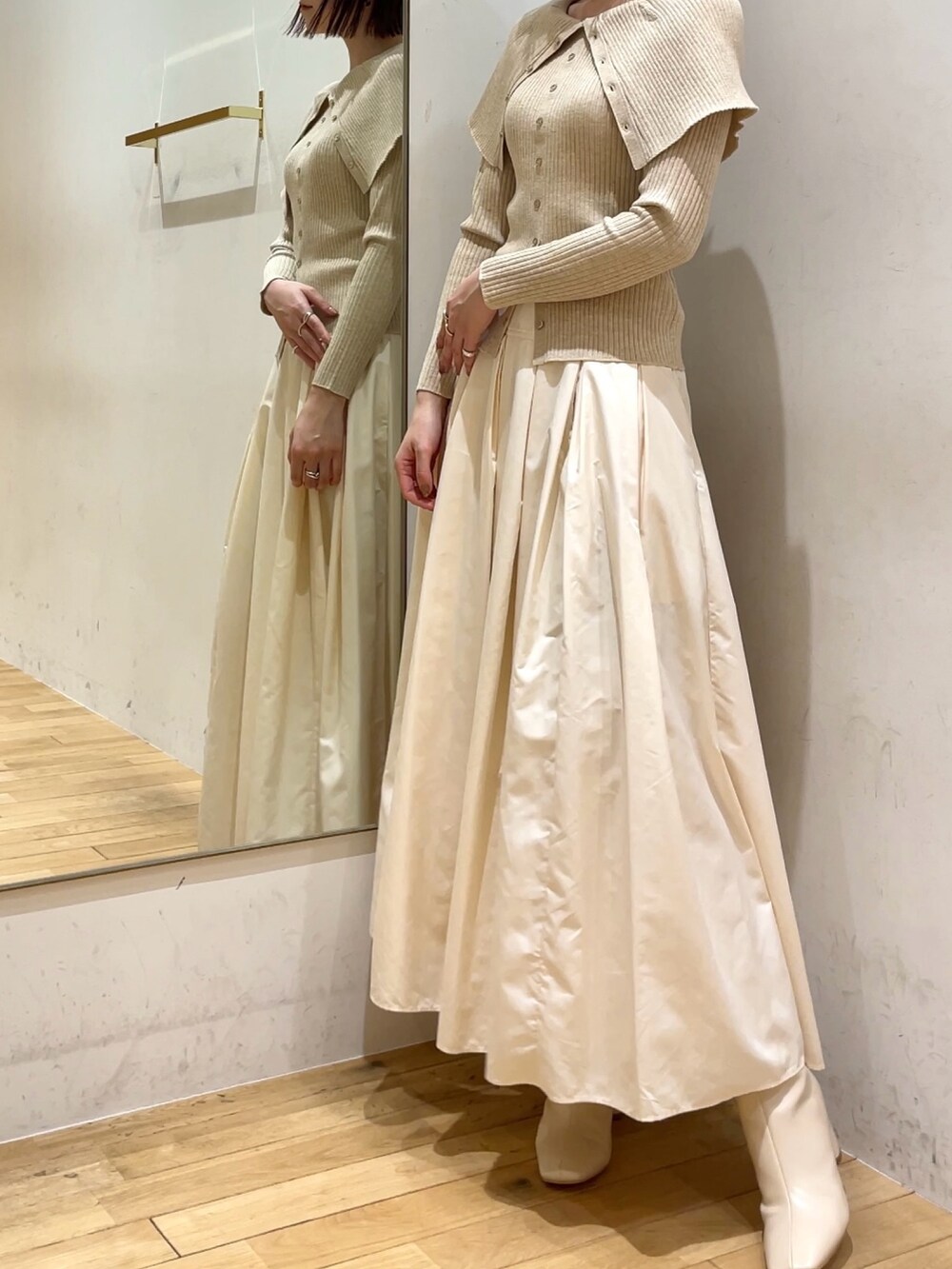 ホワイト系のブーツ、ホワイト系のスカート、ベージュ系のニット/セーターを着用したレディースの冬コーディネートの4枚目の写真