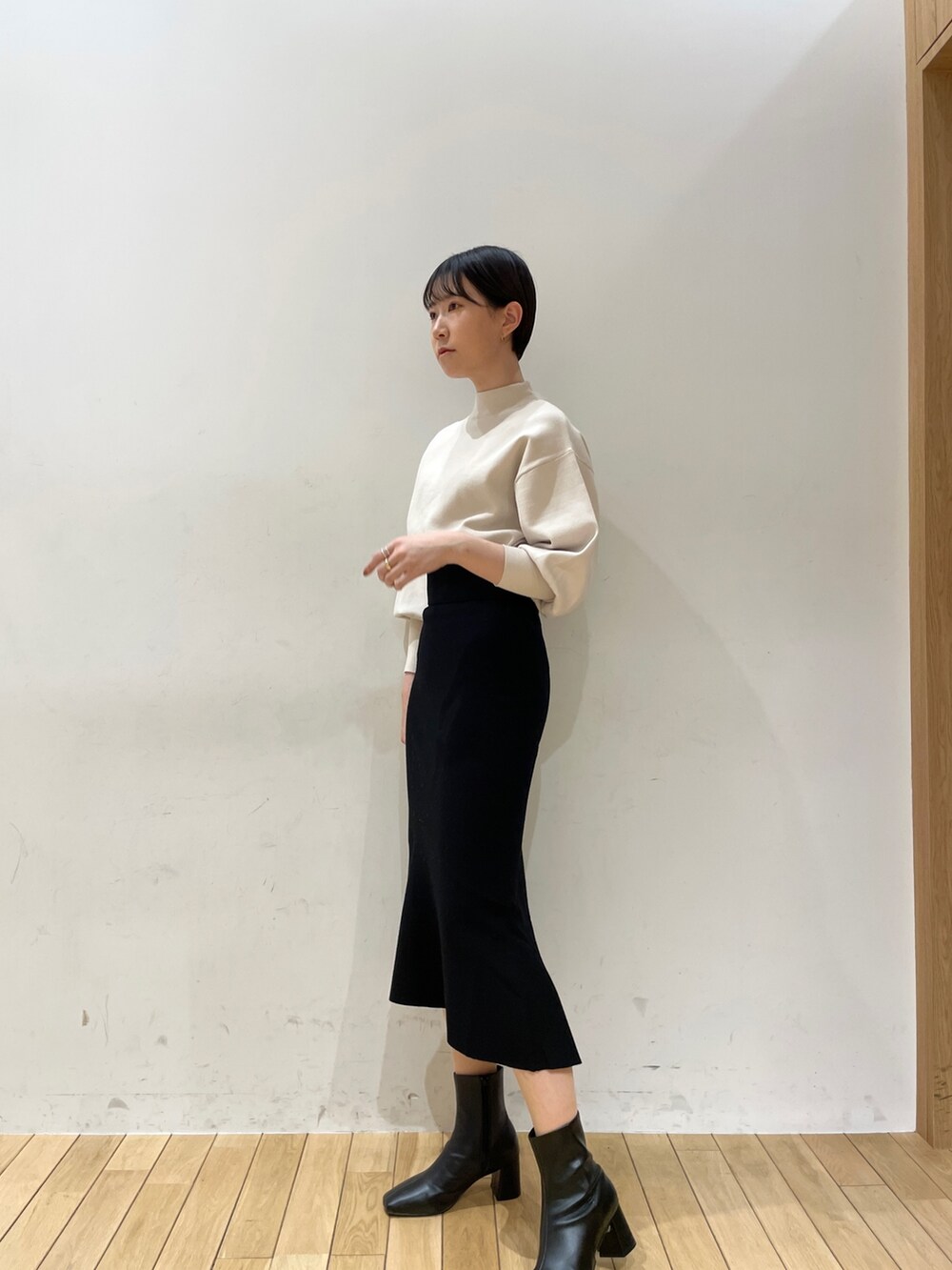 ブラック系のスカート、ホワイト系のニット/セーター、ブラック系のブーツを着用したレディースの冬コーディネートの4枚目の写真