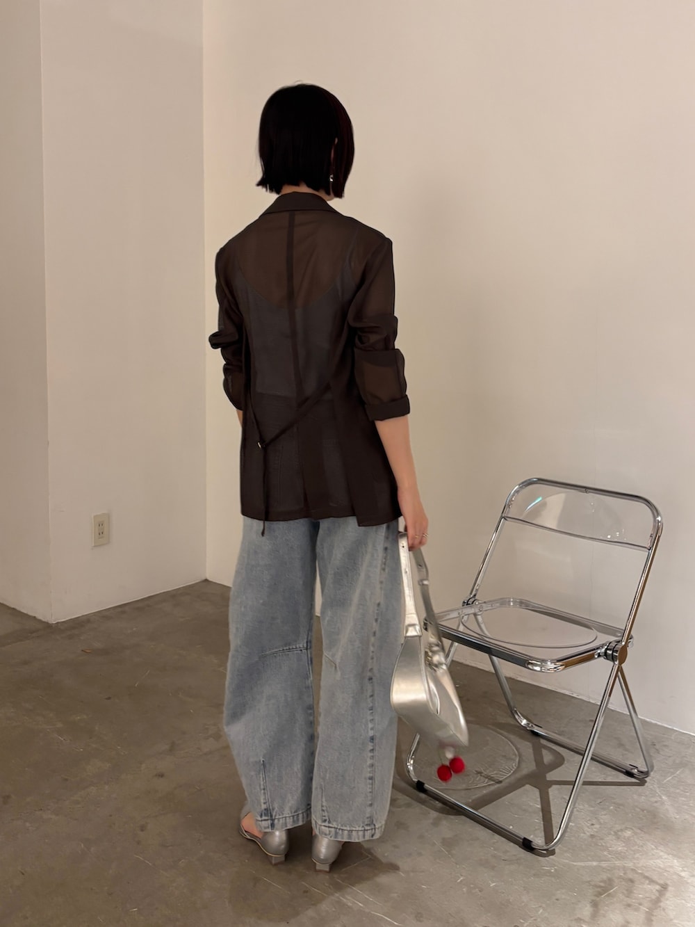 ブルー系のデニムパンツ、ブラウン系のテーラードジャケット、ブルー系のタンクトップを着用したレディースの春コーディネートの3枚目の写真