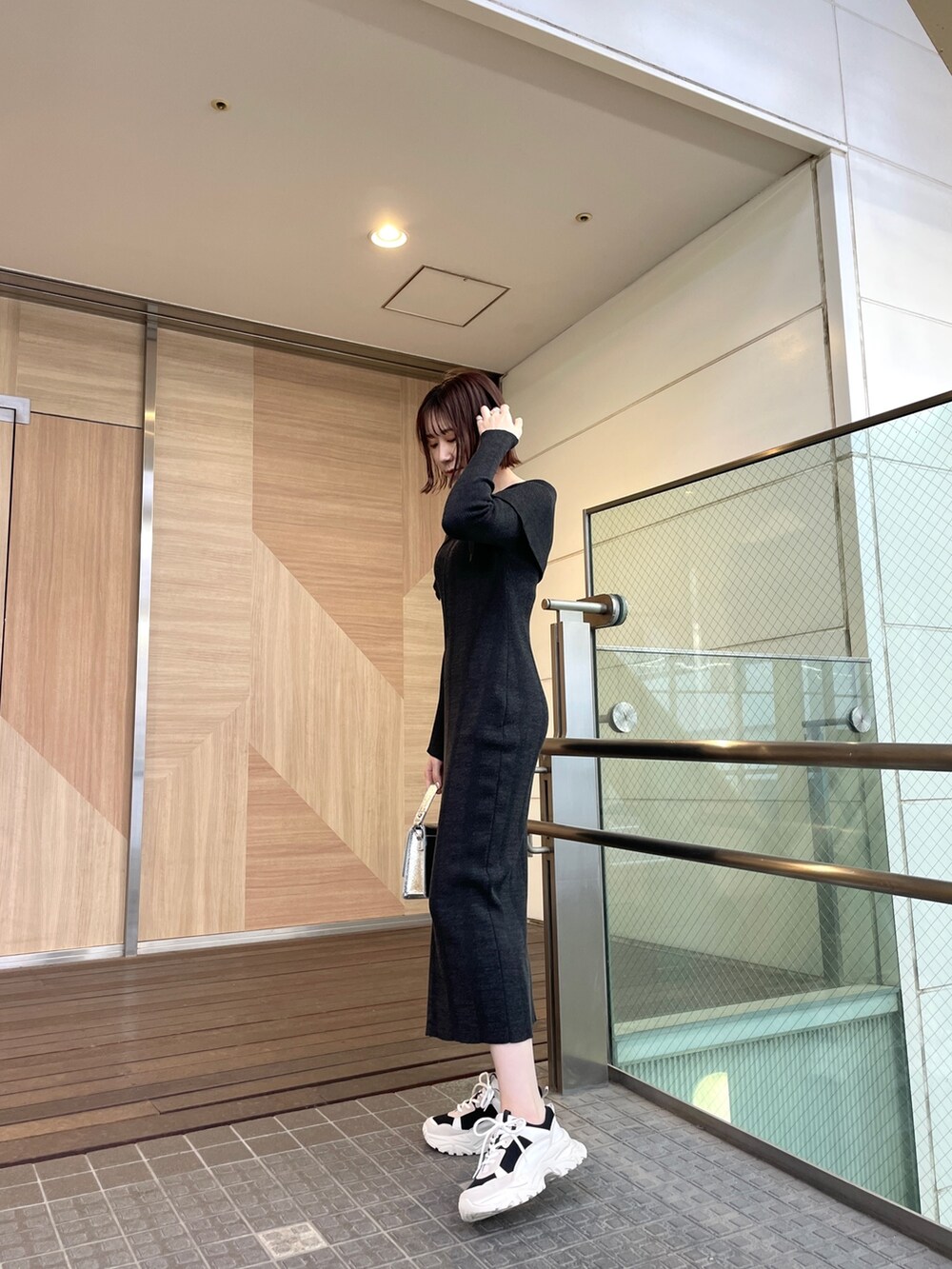 ブラック系のワンピース、ブラック系のスニーカー、シルバー系のショルダーバッグを着用したレディースの春コーディネートの3枚目の写真