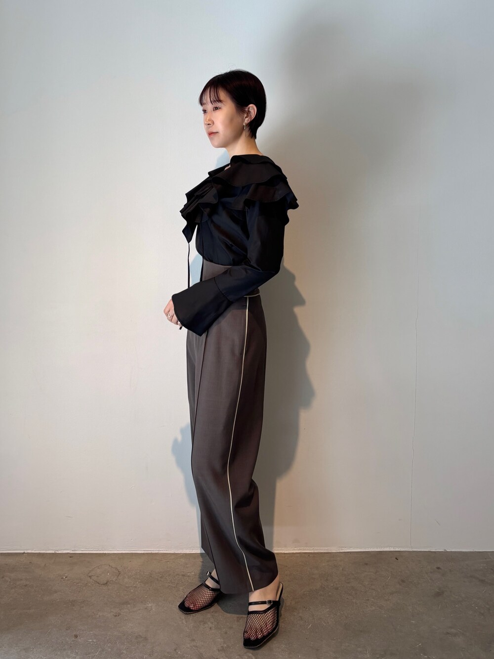 グレー系のスラックス、ブラック系のシャツ/ブラウス、ブラック系のサンダルを着用したレディースの春コーディネートの2枚目の写真