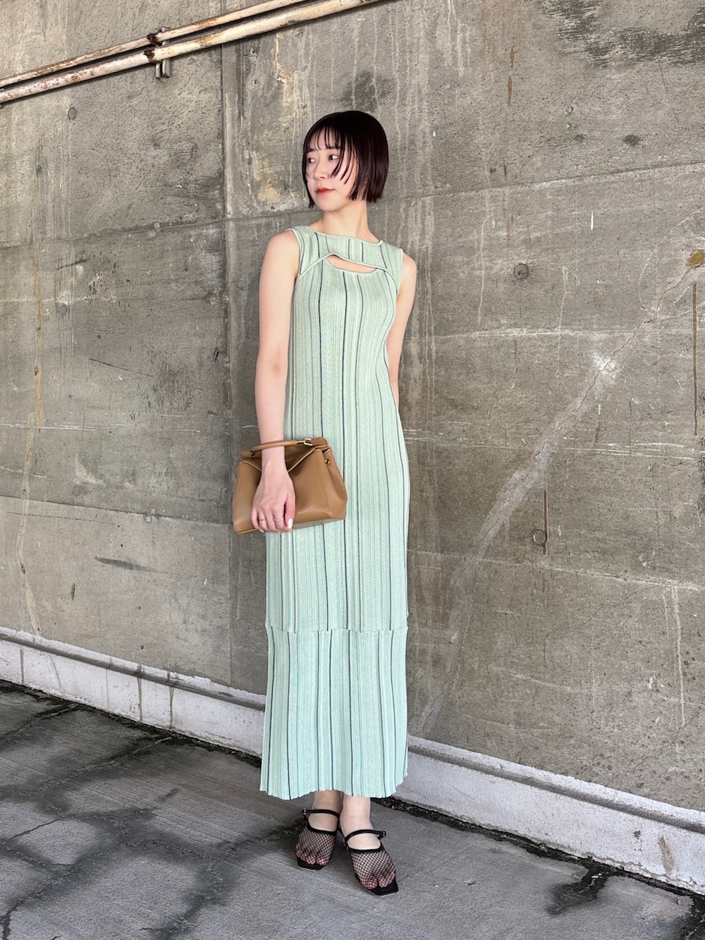 グリーン系のワンピース、ブラック系のサンダル、イエロー系のハンドバッグを着用したレディースの春コーディネートの2枚目の写真