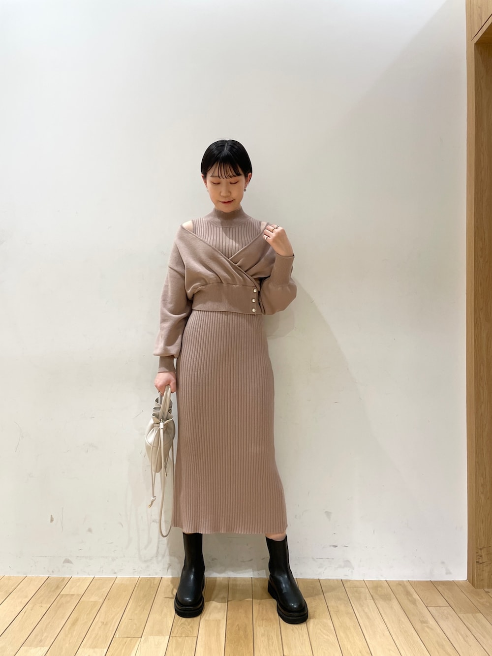 ベージュ系のワンピース、ホワイト系のハンドバッグ、ブラック系のブーツを着用したレディースの冬コーディネートの3枚目の写真