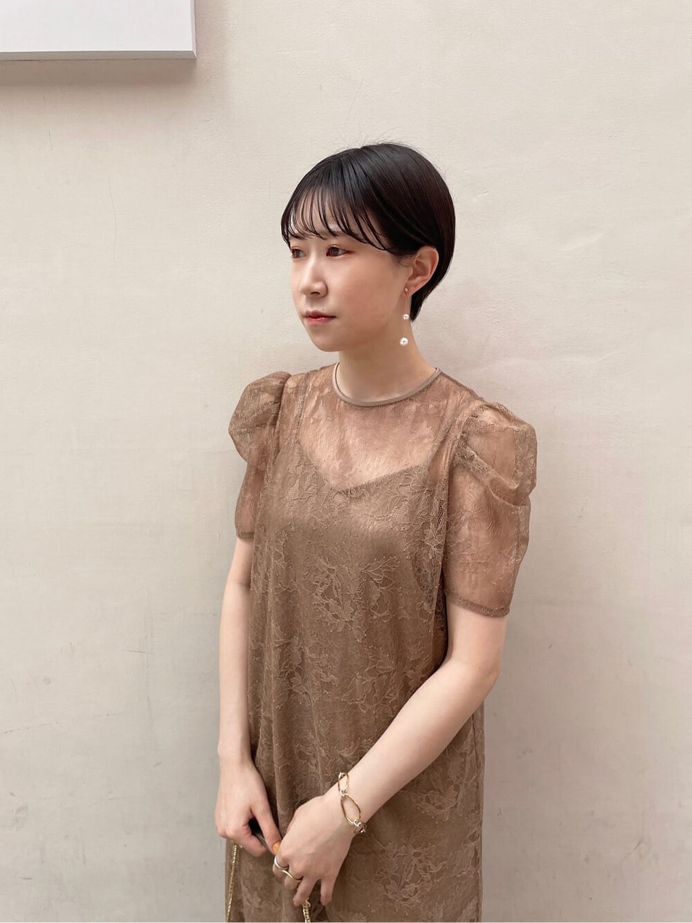 ゴールド系のパンプス、ゴールド系のクラッチバッグ、ベージュ系のドレスを着用したレディースの夏コーディネートの7枚目の写真