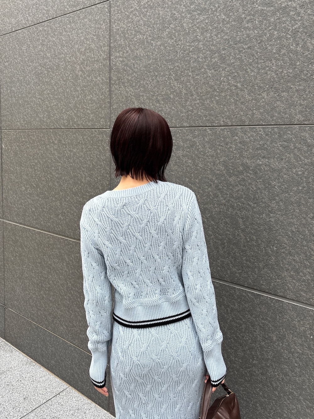 ブルー系のワンピース、ブラウン系のハンドバッグ、ブラウン系のパンプスを着用したレディースの冬コーディネートの7枚目の写真