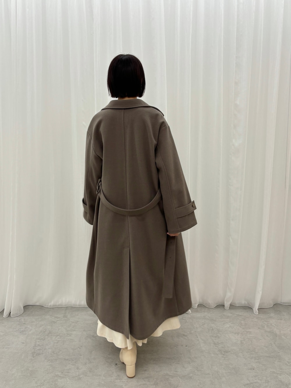 ホワイト系のスカート、ブラウン系のニット/セーター、ブラウン系のステンカラーコートを着用したレディースの秋コーディネートの3枚目の写真