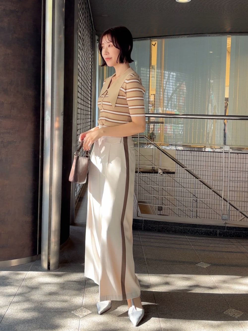 ホワイト系のその他パンツ、シルバー系のパンプス、ブラウン系のハンドバッグを着用したレディースの冬コーディネートの3枚目の写真