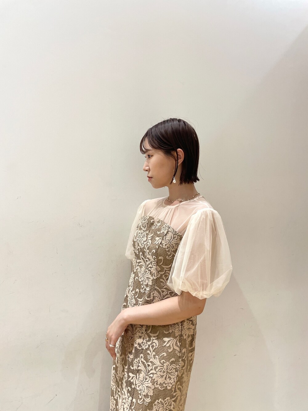 ベージュ系のハンドバッグ、ベージュ系のパンプス、ベージュ系のドレスを着用したレディースの秋コーディネートの9枚目の写真