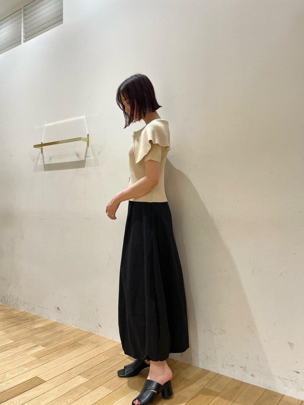 ブラック系のサンダル、ホワイト系のニット/セーター、ブラック系のスカートを着用したレディースの夏コーディネートの4枚目の写真