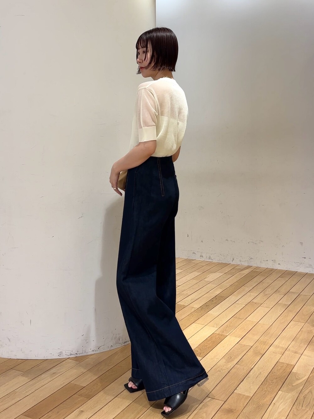 ブルー系のデニムパンツ、イエロー系のハンドバッグ、ブラック系のサンダルを着用したレディースの春コーディネートの2枚目の写真