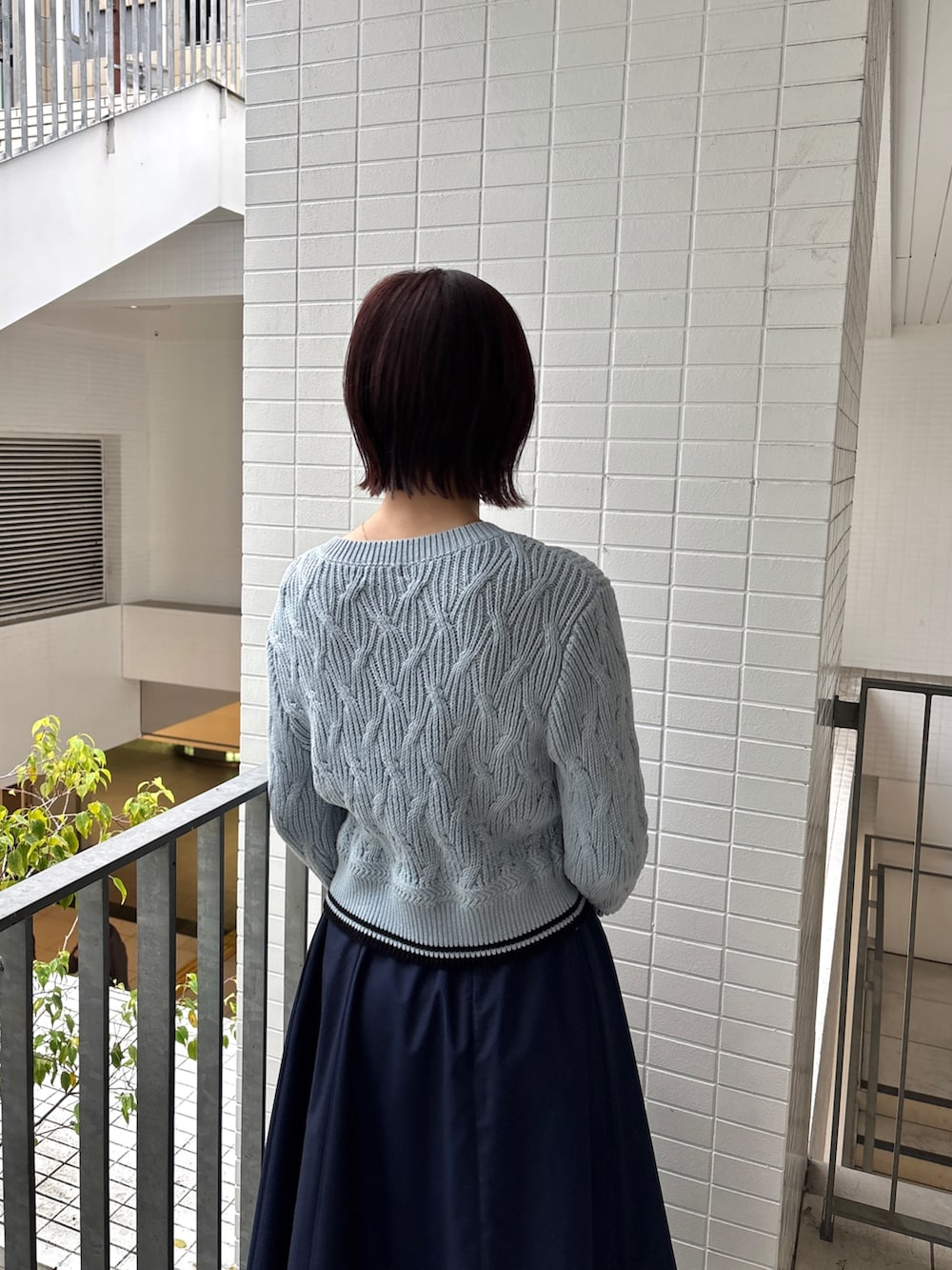 ブルー系のスカート、ブルー系のワンピース、ブラウン系のハンドバッグを着用したレディースの春コーディネートの5枚目の写真