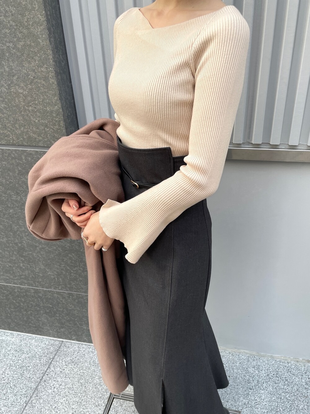 ホワイト系のニット/セーター、ブラウン系のチェスターコート、グレー系のスカートを着用したレディースの冬コーディネートの5枚目の写真