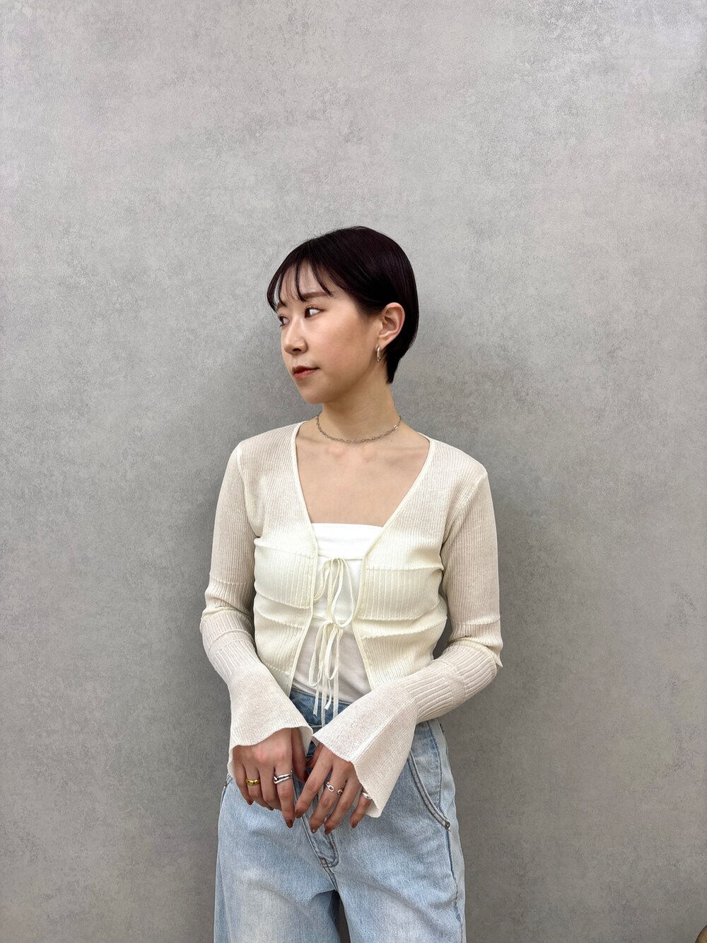 ブルー系のデニムパンツ、ホワイト系のカーディガン/ボレロ、ホワイト系のサンダルを着用したレディースの春コーディネートの5枚目の写真