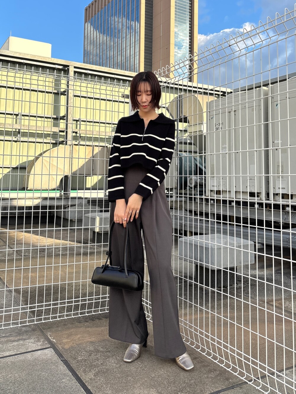 グレー系のその他パンツ、ブラック系のニット/セーター、グレー系のムートンコートを着用したレディースの冬コーディネートの2枚目の写真