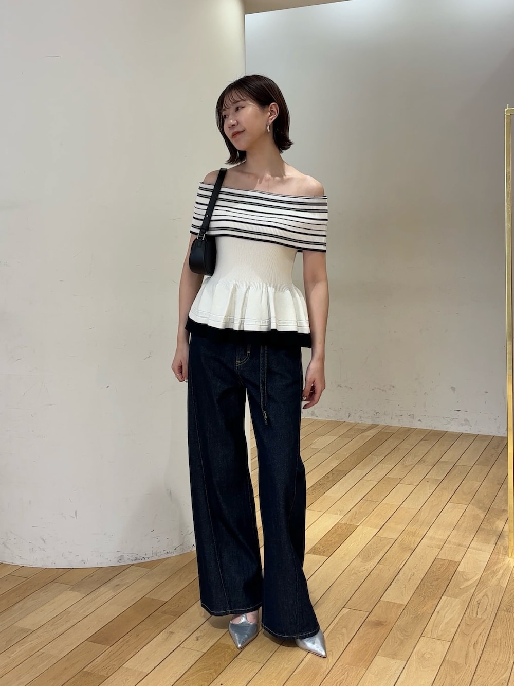 ホワイト系のニット/セーター、ブルー系のデニムパンツ、ブラック系のハンドバッグを着用したレディースの夏コーディネートの2枚目の写真
