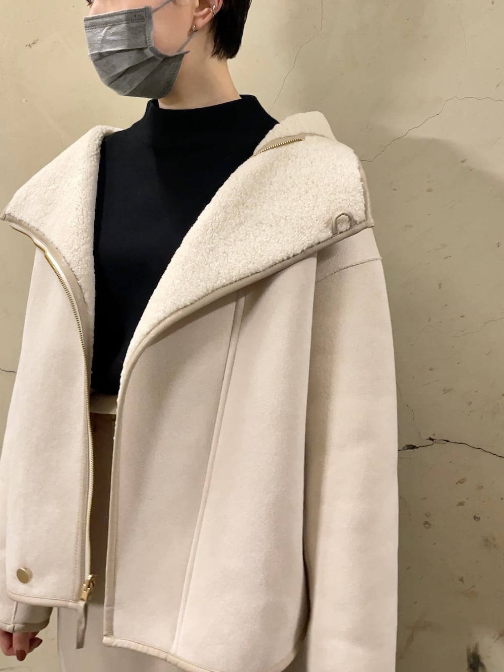 ホワイト系のブルゾン、ブラック系のブーツ、ベージュ系のスカートを着用したレディースの秋コーディネートの7枚目の写真