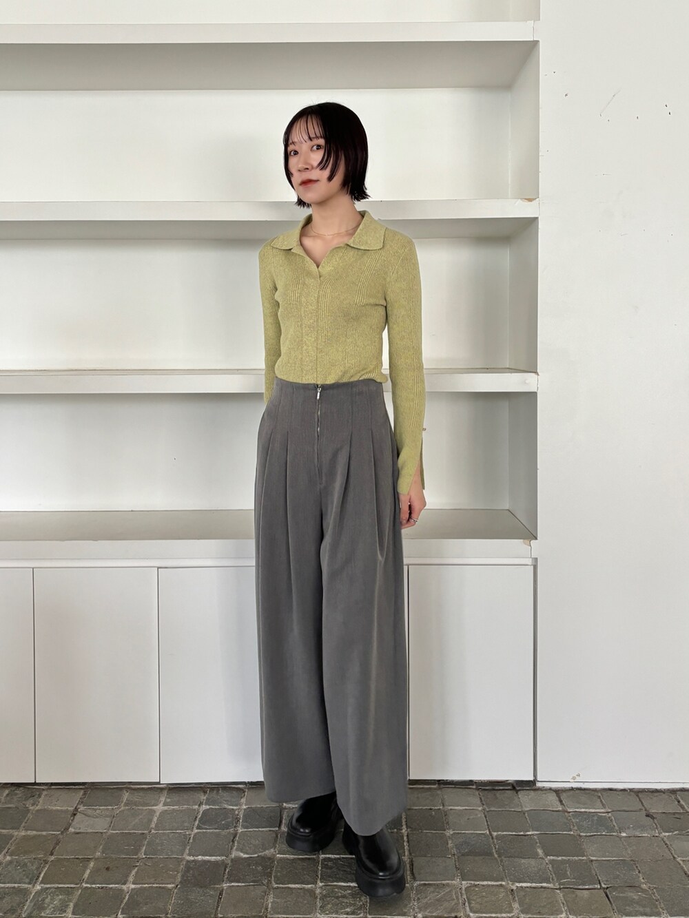 ブラック系のブーツ、グレー系のその他パンツ、グリーン系のニット/セーターを着用したレディースの冬コーディネートの2枚目の写真