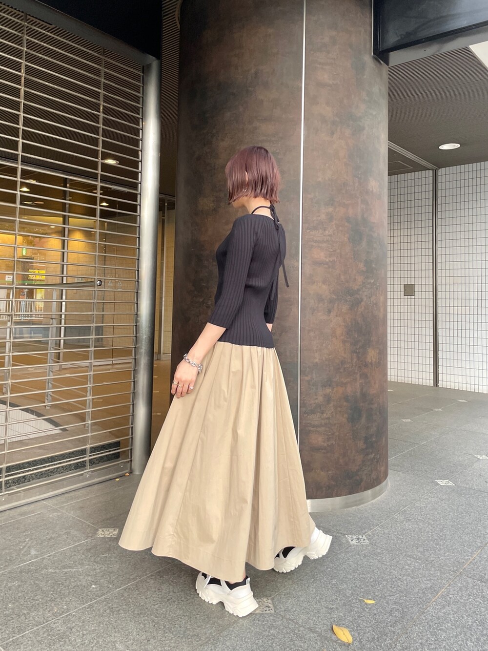 ブラック系のスニーカー、ブラック系のニット/セーター、ベージュ系のスカートを着用したレディースの春コーディネートの3枚目の写真