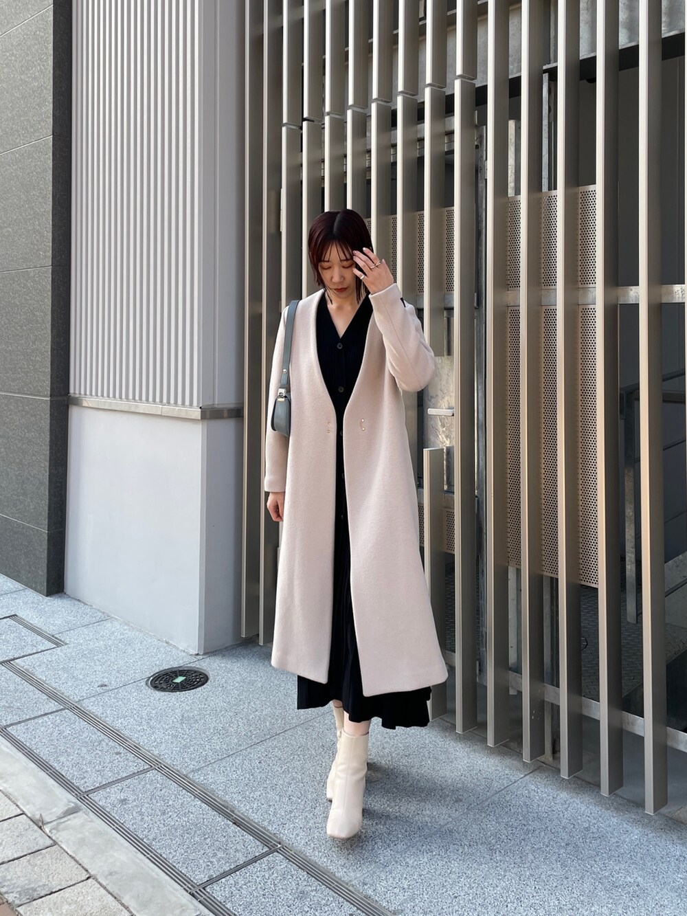 ブラック系のワンピース、ブルー系のショルダーバッグ、ホワイト系のブーツを着用したレディースの冬コーディネートの6枚目の写真