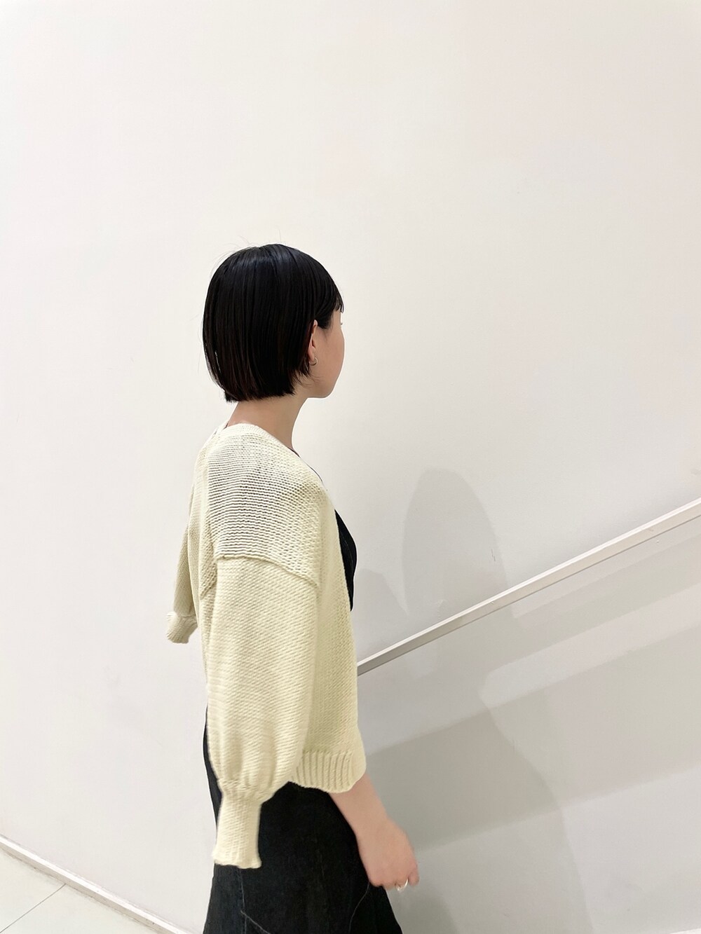 ブラック系のワンピース、ベージュ系のカーディガン/ボレロを着用したレディースの春コーディネートの6枚目の写真