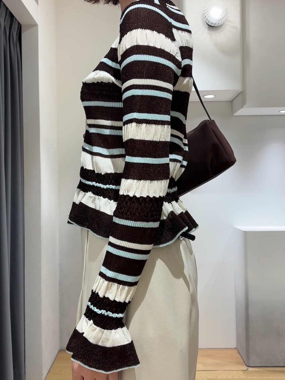 ホワイト系のその他パンツ、ブラウン系のカーディガン/ボレロ、ブラック系のブーツを着用したレディースの秋コーディネートの6枚目の写真